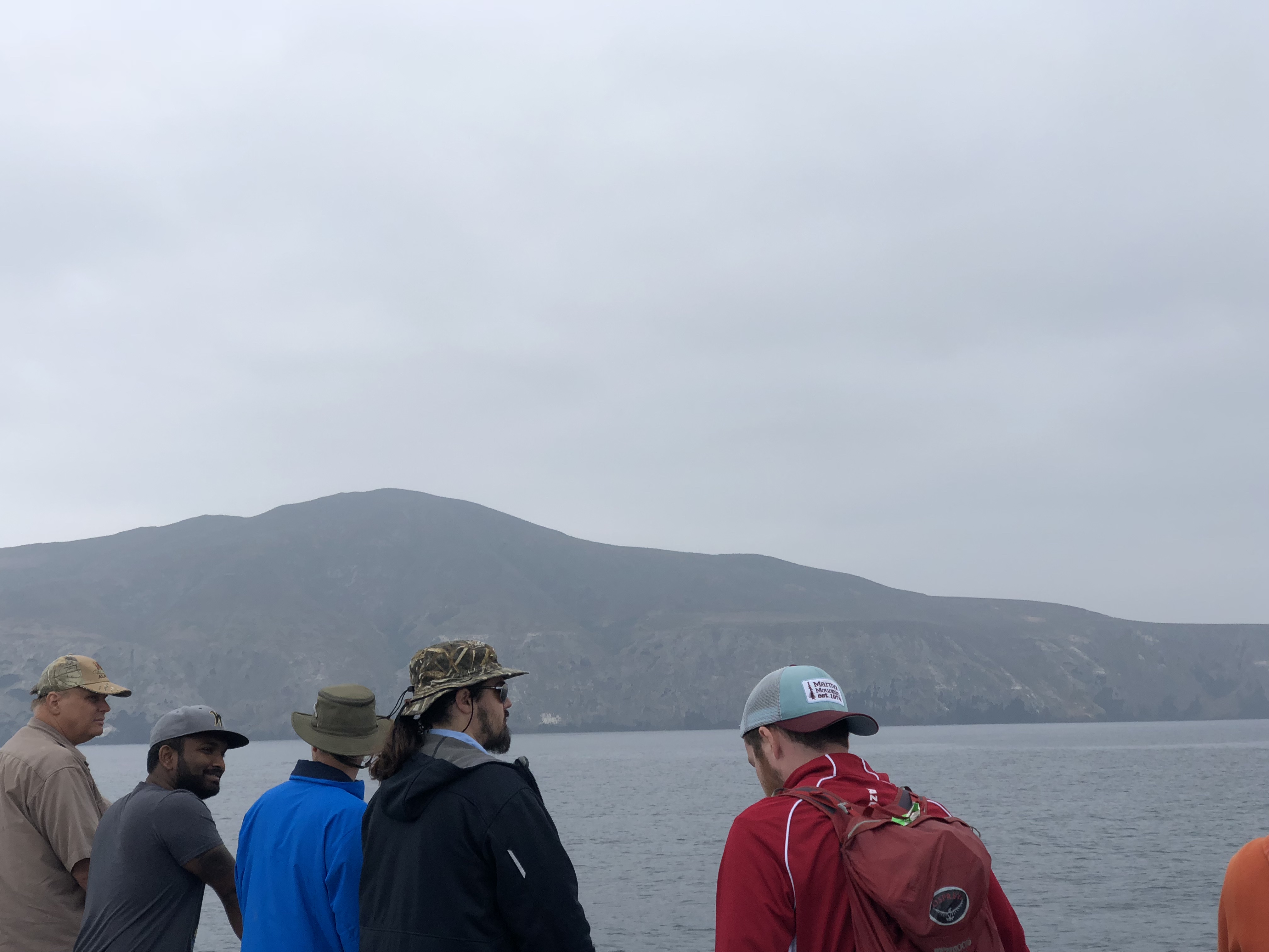 Anglers at the rail of a sportfishing boat with the rolling hills of Santa Cruz Island rising behind them
