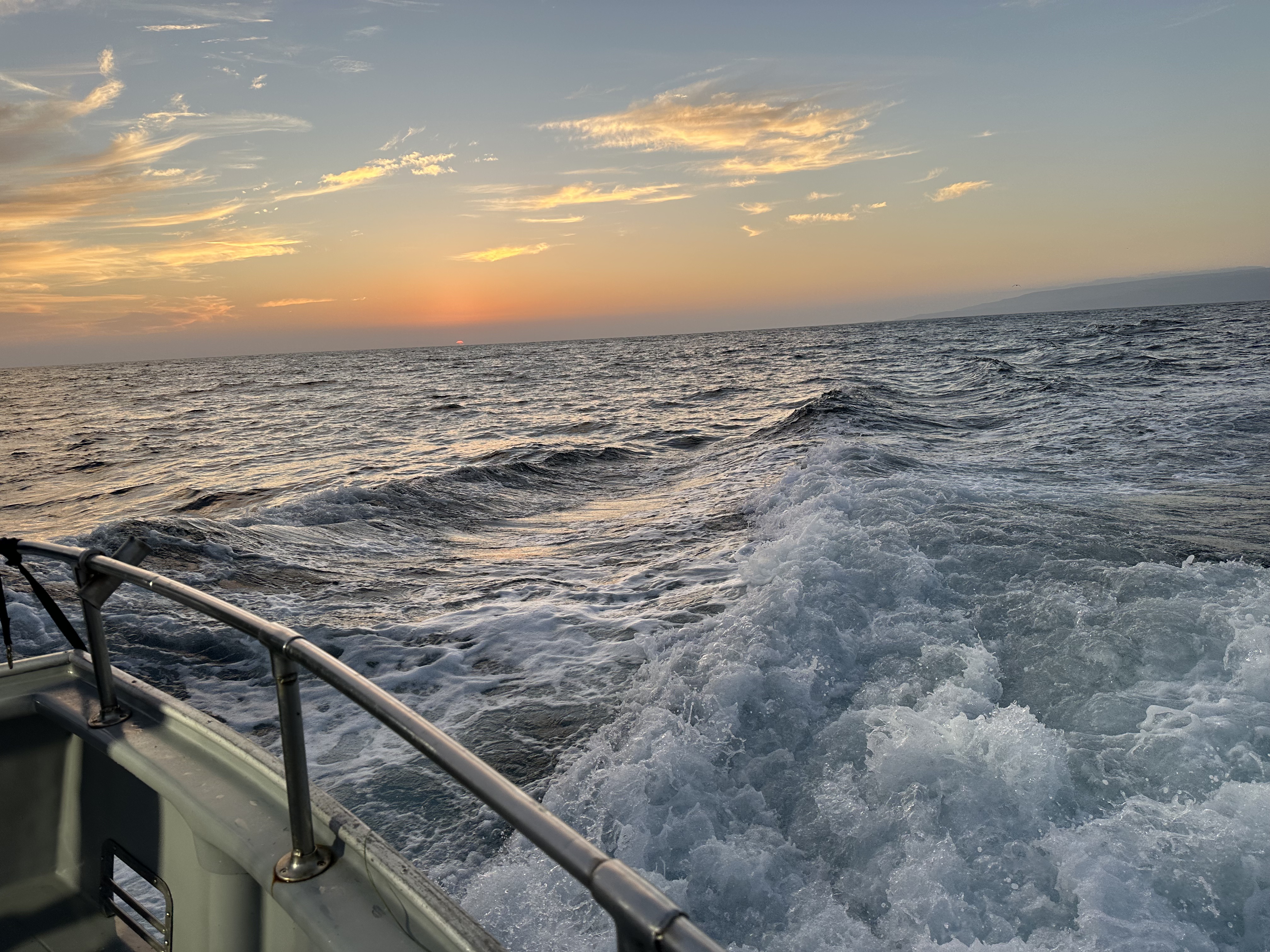 Sunrise over the open ocean with the boat's wake churning behind, on the run to Catalina