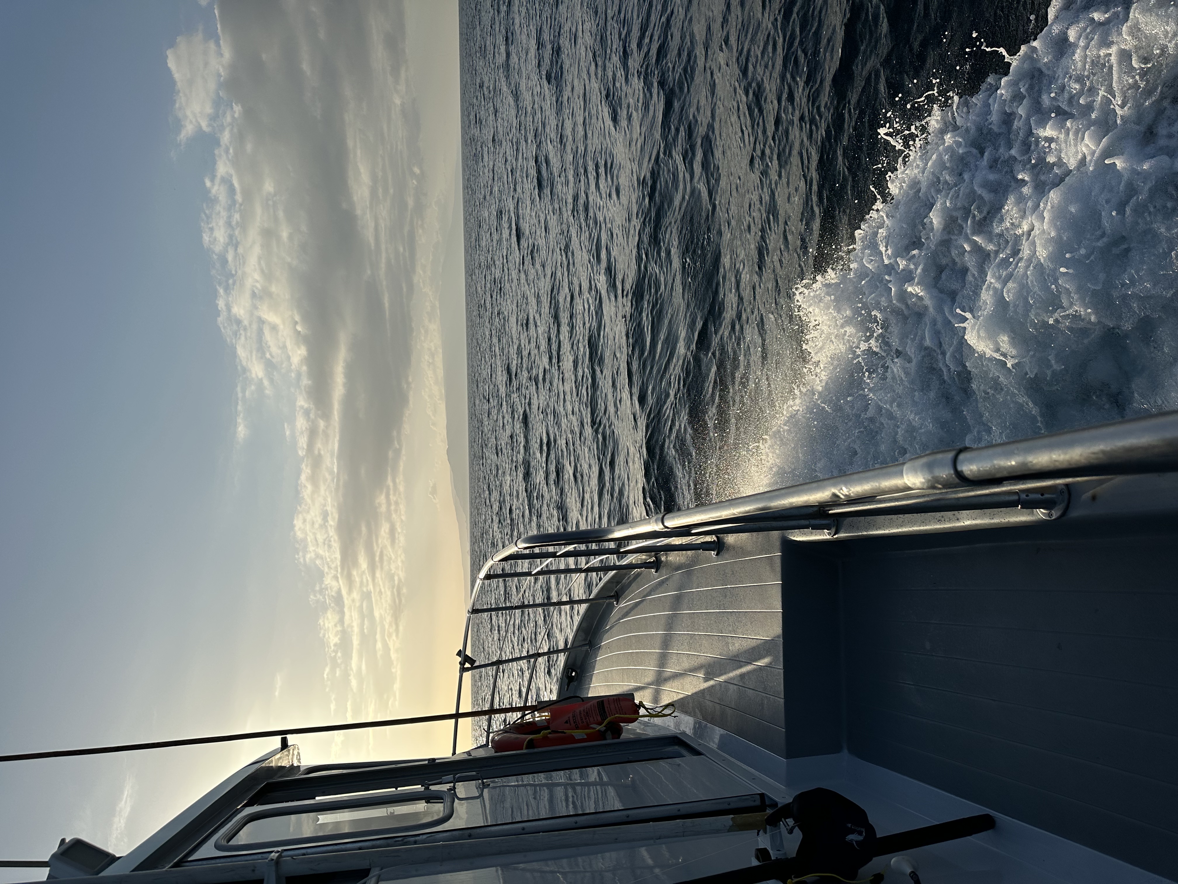 The side rail and wake of a sportfishing boat underway in golden light, Catalina on the horizon