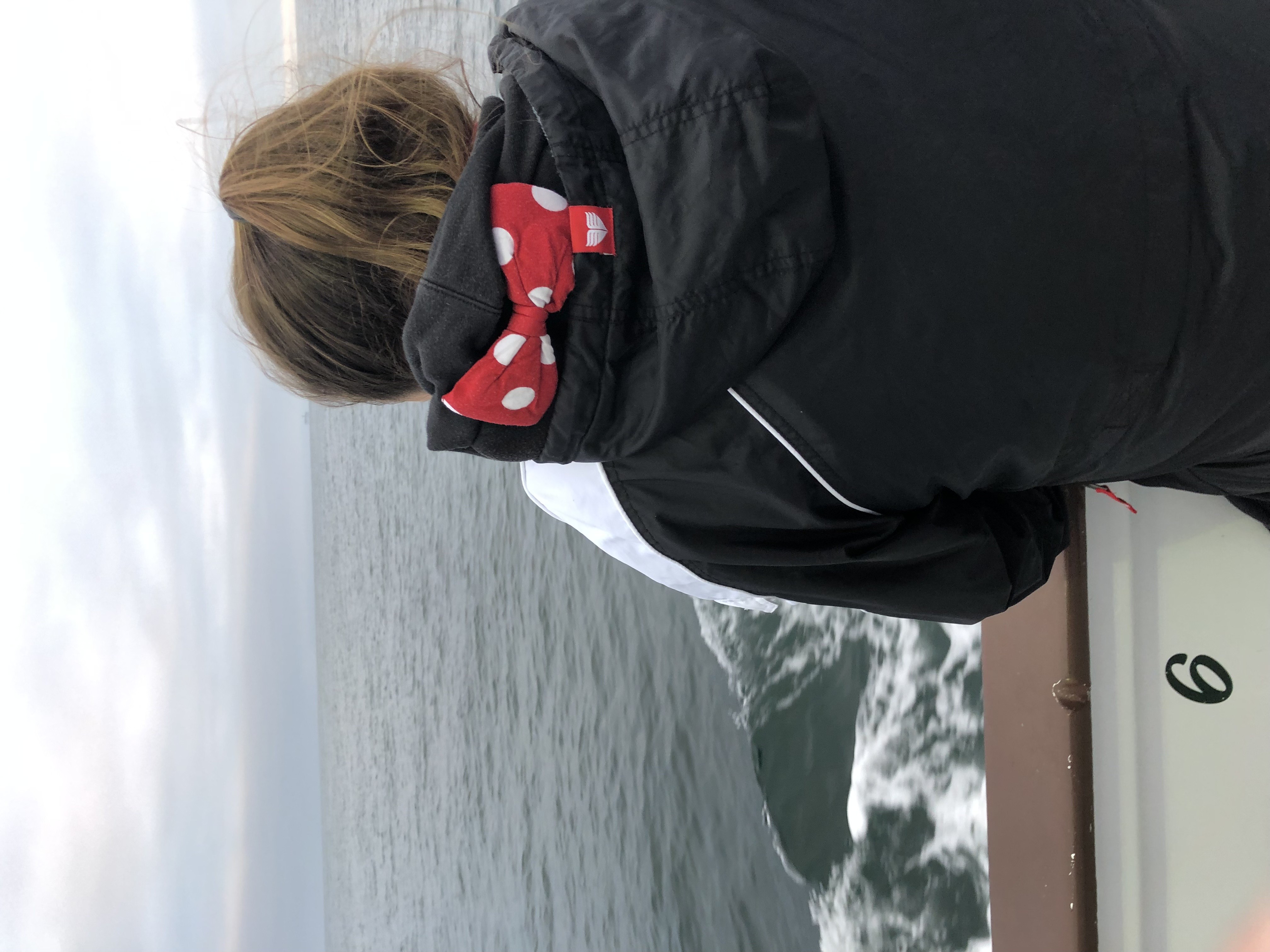 Author's daughter from behind, ponytail with a polka-dot bow, watching the wake of the boat trail behind on a SoCal sportfishing trip