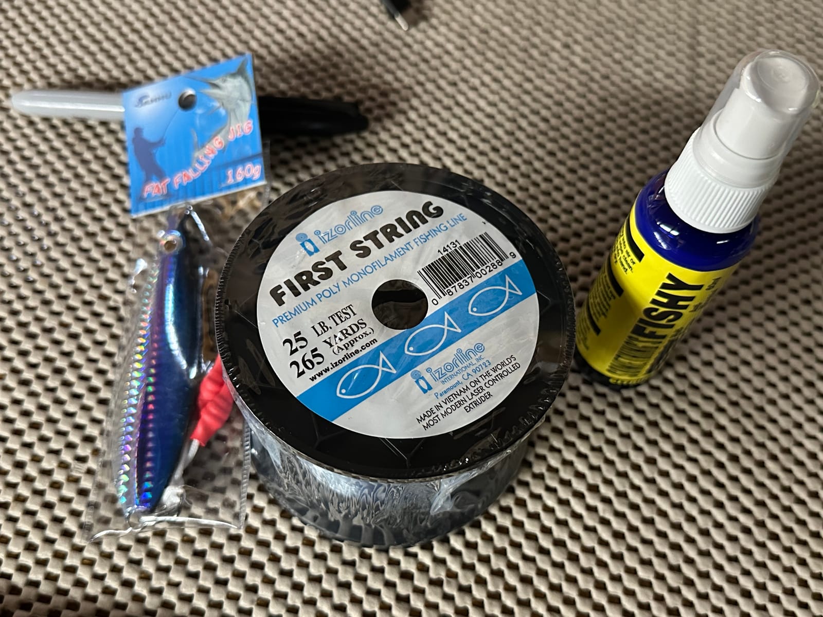 An Izorline First String 25-pound monofilament spool, a flat-fall jig, and a Something's Fishy bait spray on the deck of the Horizon