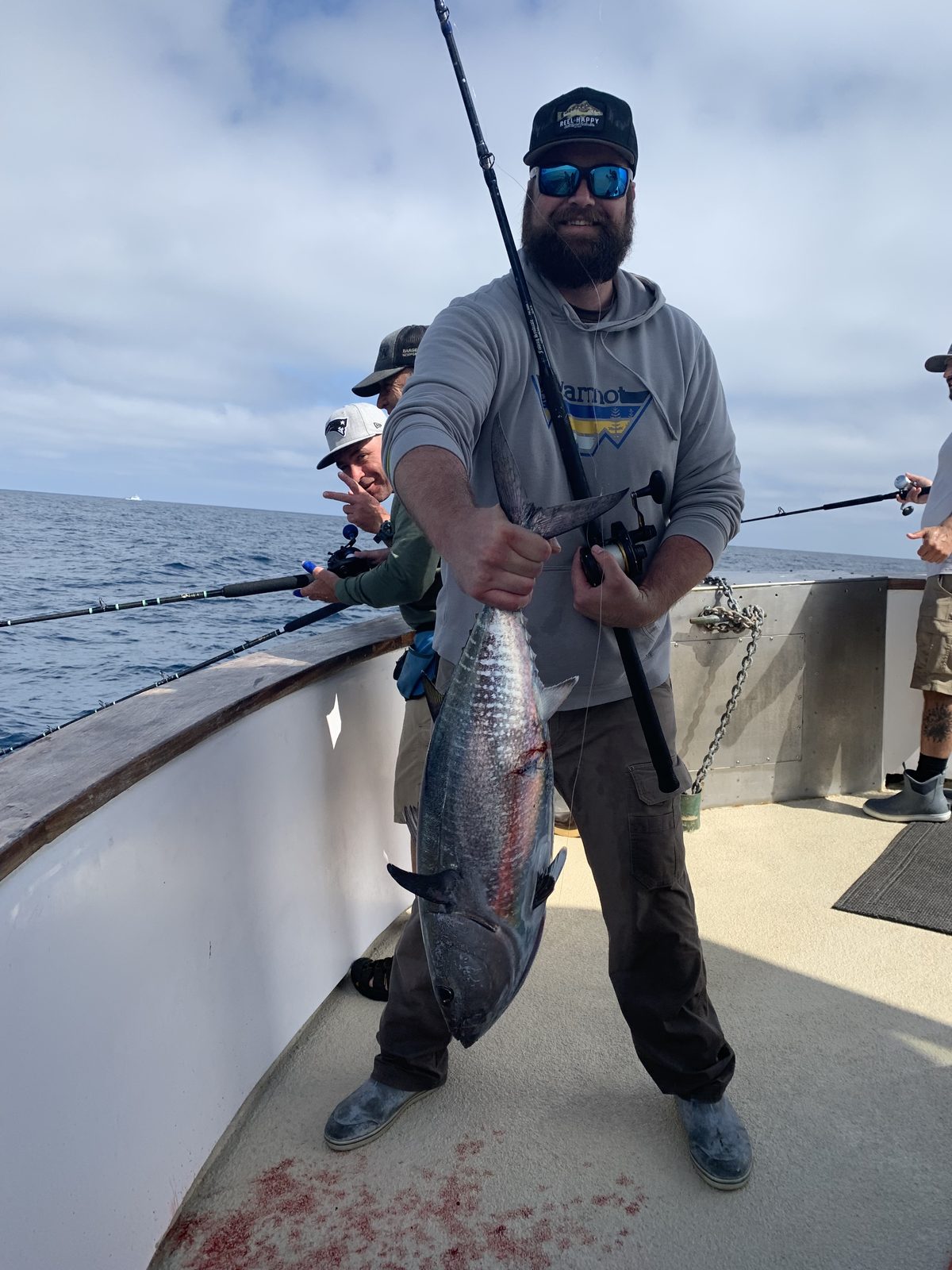 An angler on the boat holds up a bluefin tuna caught offshore of San Diego